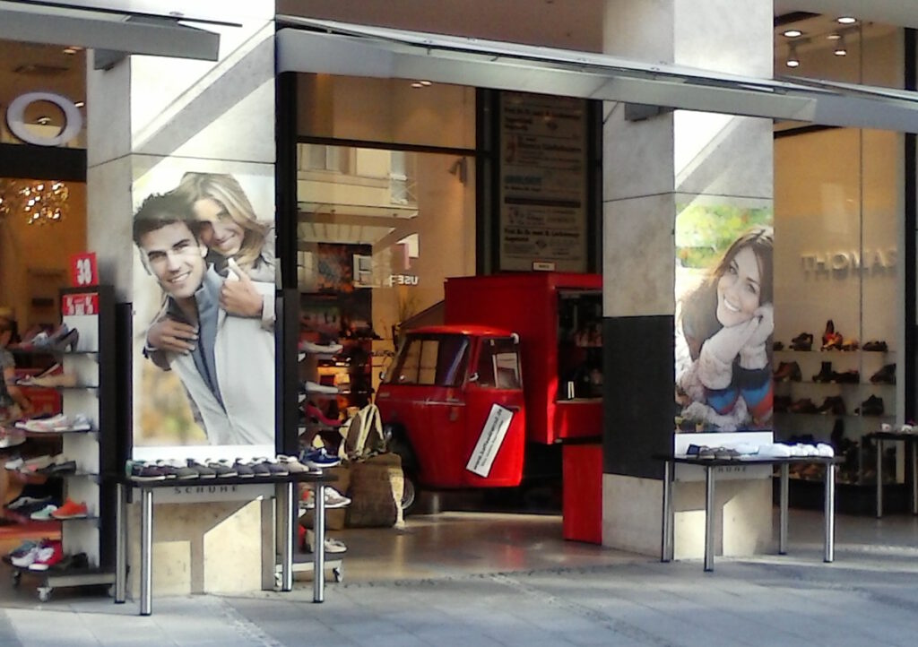 06 rotes Espressomobil unter Arkaden Schuh Geschäft macht Promotion in einer Fußgängerzone