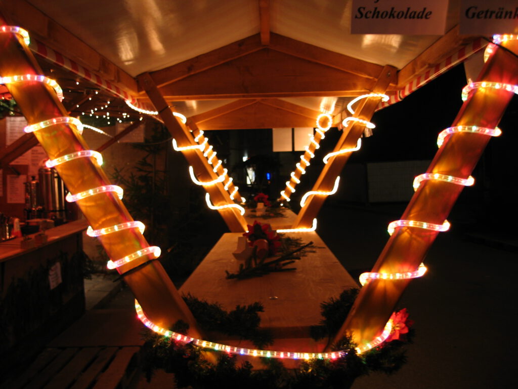 29 überdachter beleuchteter Holztisch am Weihnachtsmarkt für Glühwein und heißen Caiprinha